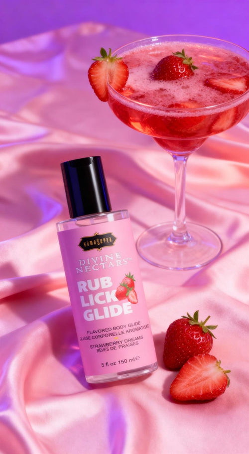 Bottle of 'Rub Lick Glide' with a strawberry-flavored body glaze, surrounded by strawberries on a pink fabric background.