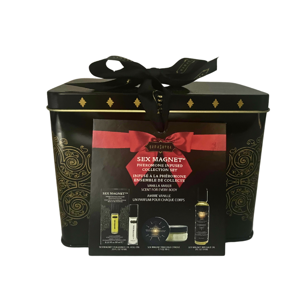 A product image featuring a black tin container tied with a black ribbon. The tin includes a pheromone fragrance roll-on, massage oil, and a massage candle, all scented with vanilla amber.
