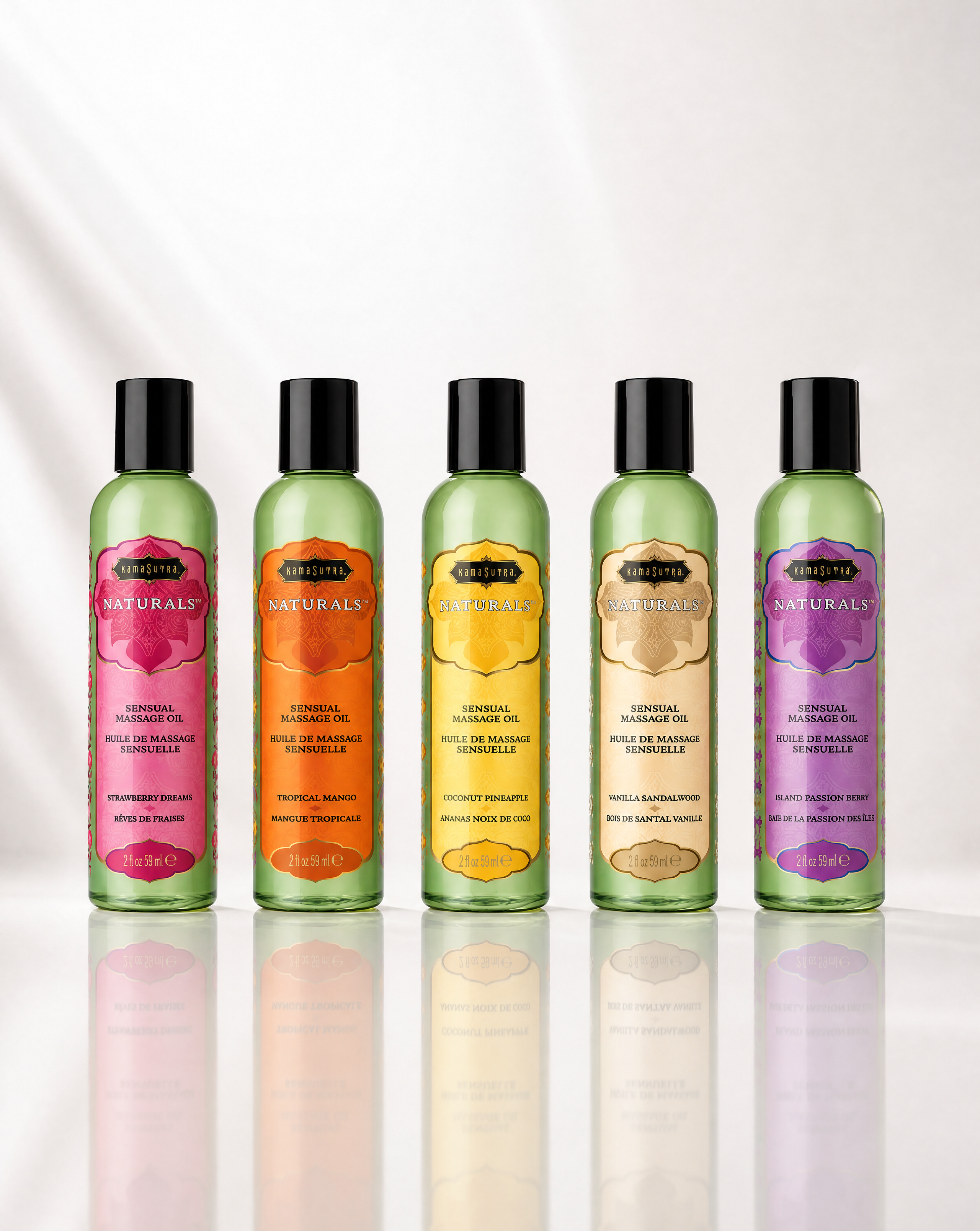 A lineup of five Naturals Massage Oil bottles in various fruit-themed labels, including Strawberry Dreams, Tropical Mango, Coconut Pineapple, Vanilla Sandalwood, and Island Passion Berry.