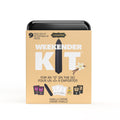 The image displays the packaging of the "Vibe Weekender Kit," which is presented as a compact, travel-friendly set designed for intimate pleasure on-the-go. The kit is depicted in a vibrant orange color with bold white and green text that highlights its contents and features. Shown in creme color representing Vanilla Creme flavor.