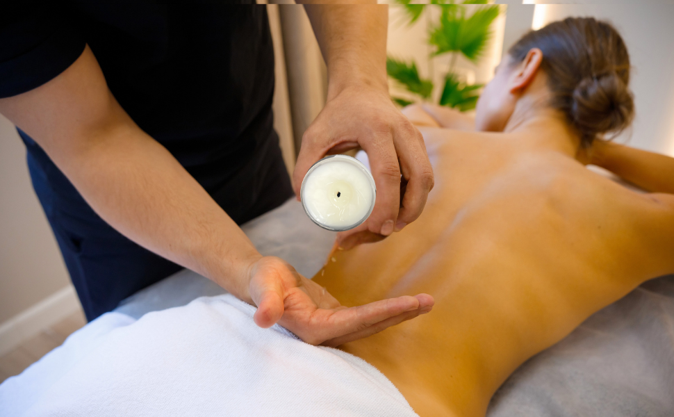 Person applying a candle to another person's back during a massage.