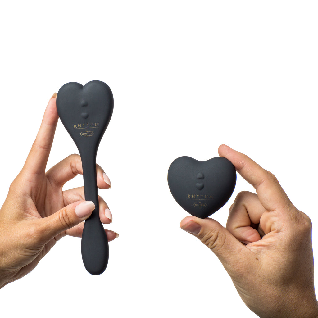 Natya  couples toy in black color. heart shaped remote and flexible toy in models hands- The Kama Sutra Company