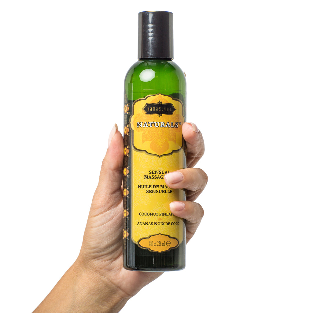 Naturals Massage Oil (8oz) Coconut Pinapple shown in models hand - The Kama Sutra Company