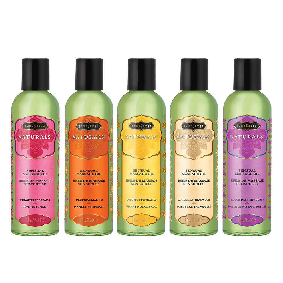 A lineup of five Naturals Massage Oil bottles in various fruit-themed labels, including Strawberry Dreams, Tropical Mango, Coconut Pineapple, Vanilla Sandalwood, and Island Passion Berry.