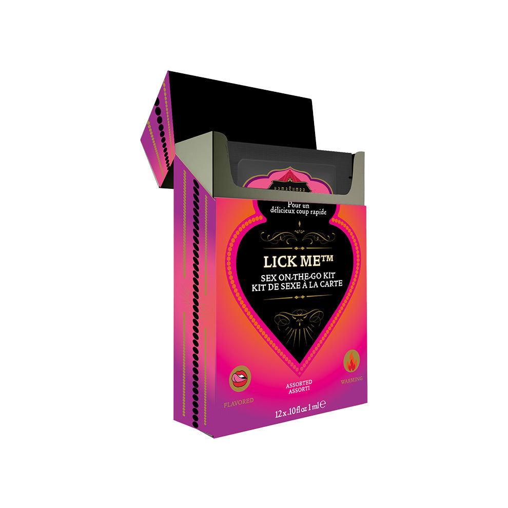 The image displays the packaging of the Kama Sutra LICK ME Sex-To-Go Kit. The box is predominantly pink and purple, with a heart shape in the center that contains the product name "LICK ME". Box iss shown open revealing packets